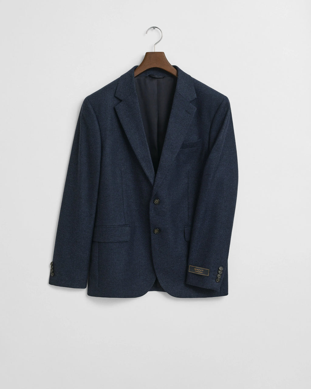 Navy blazer on a hanger against a light gray background