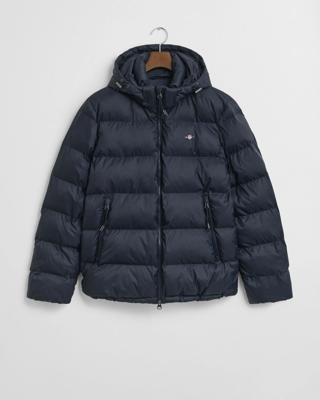 Navy puffer jacket on a hanger against a light gray background