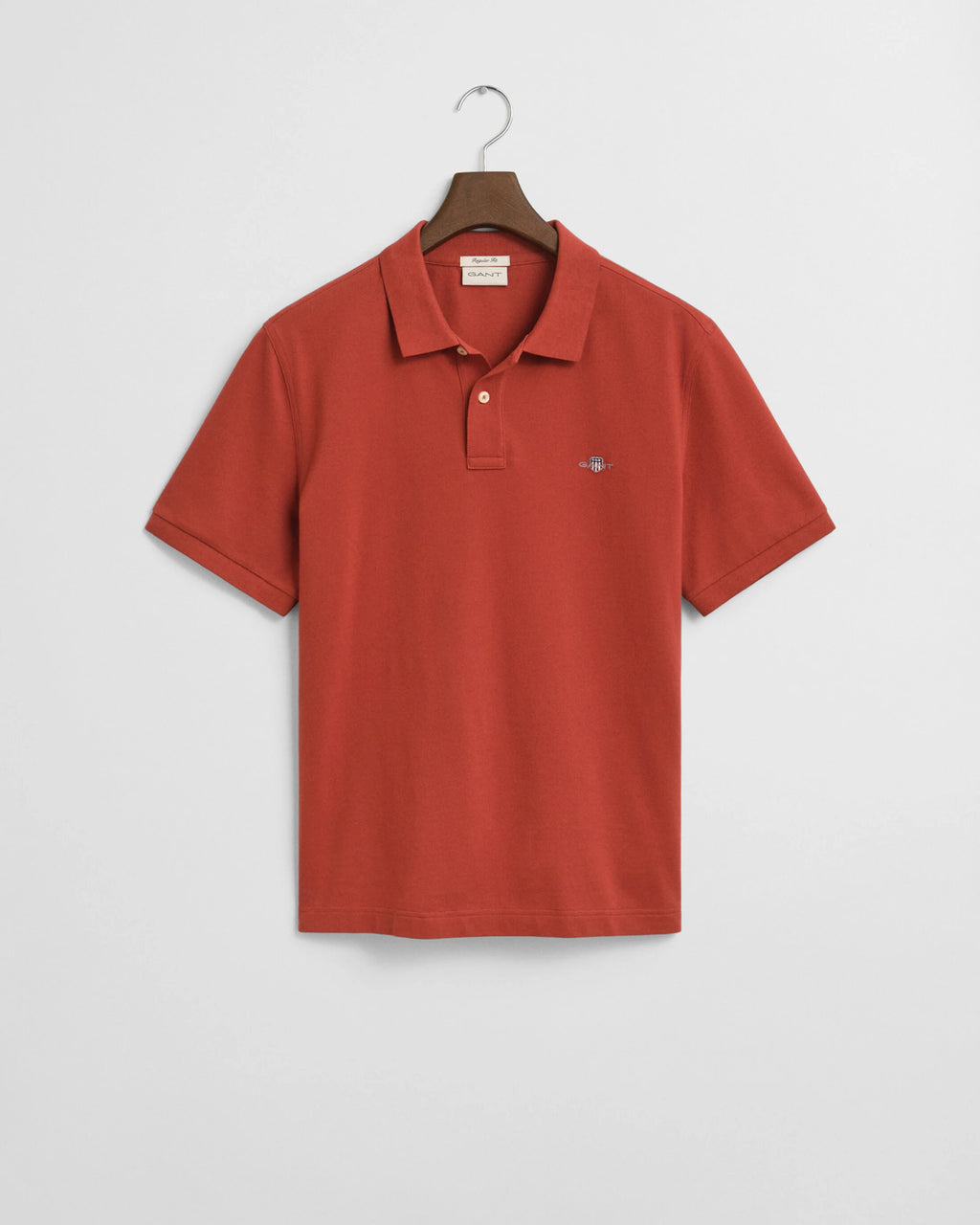 Red polo shirt on a hanger against a light gray background