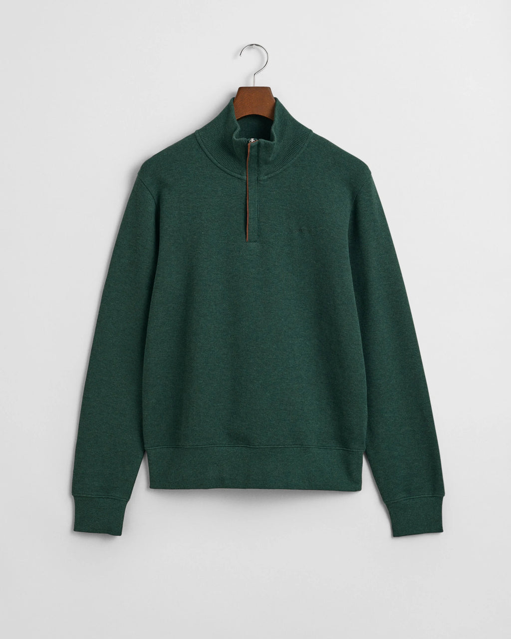 Green sweater on a hanger against a light gray background