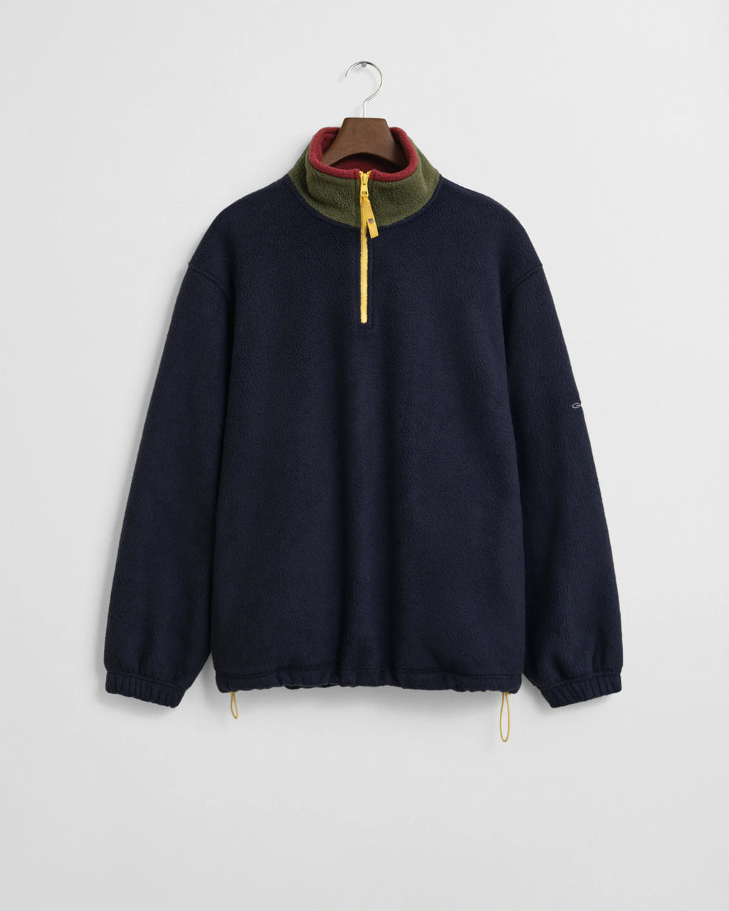 Navy blue pullover with a colorful collar on a hanger against a light gray background
