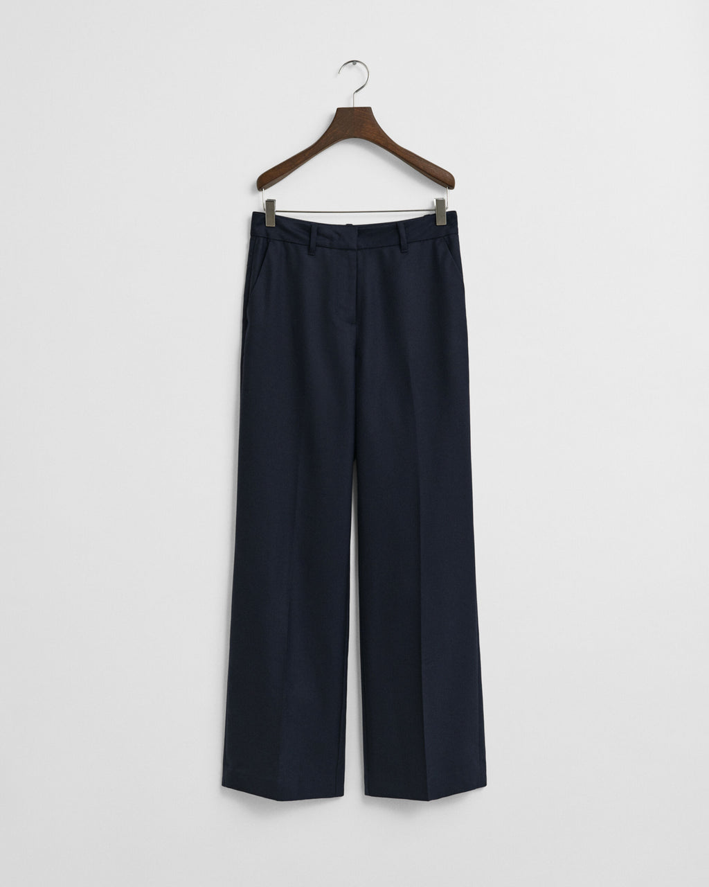 Navy blue pants on a wooden hanger against a white background