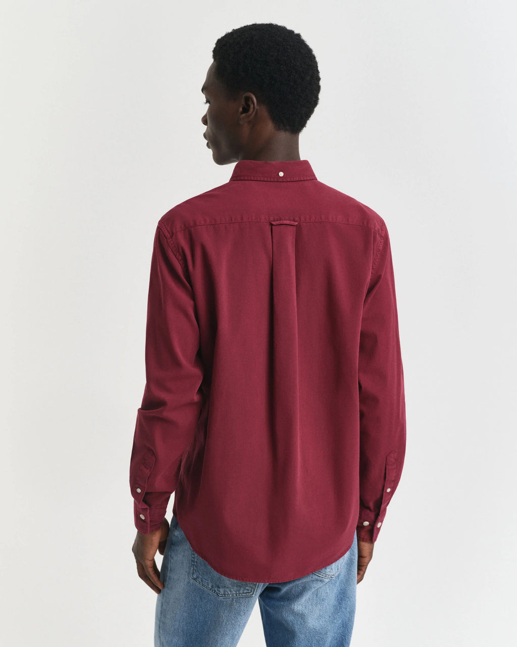 Person wearing a red shirt and blue jeans on a white background