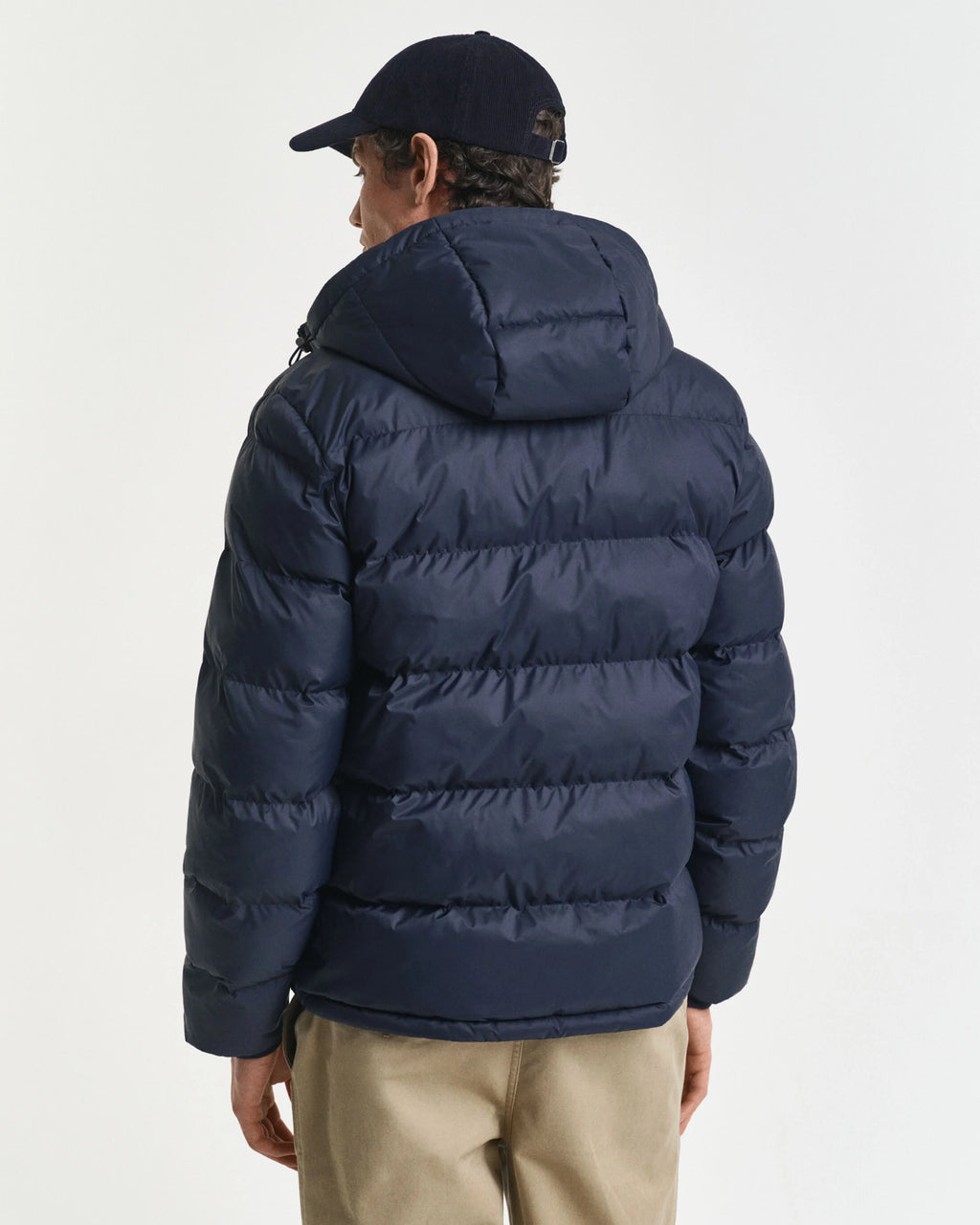 Person wearing a navy blue puffer jacket on a light gray background