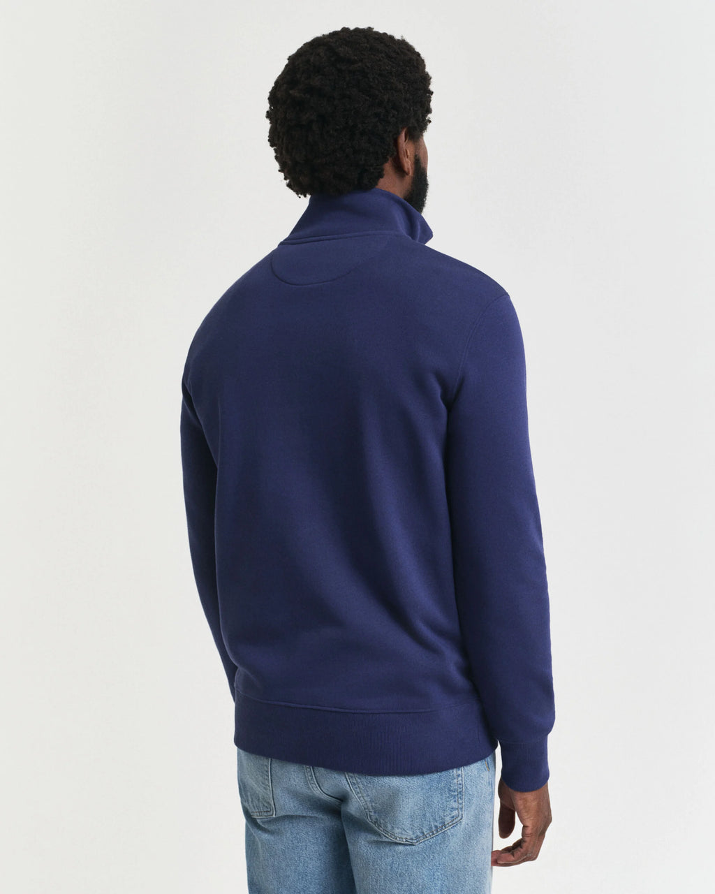 Person wearing a blue half-zip sweatshirt on a light gray background