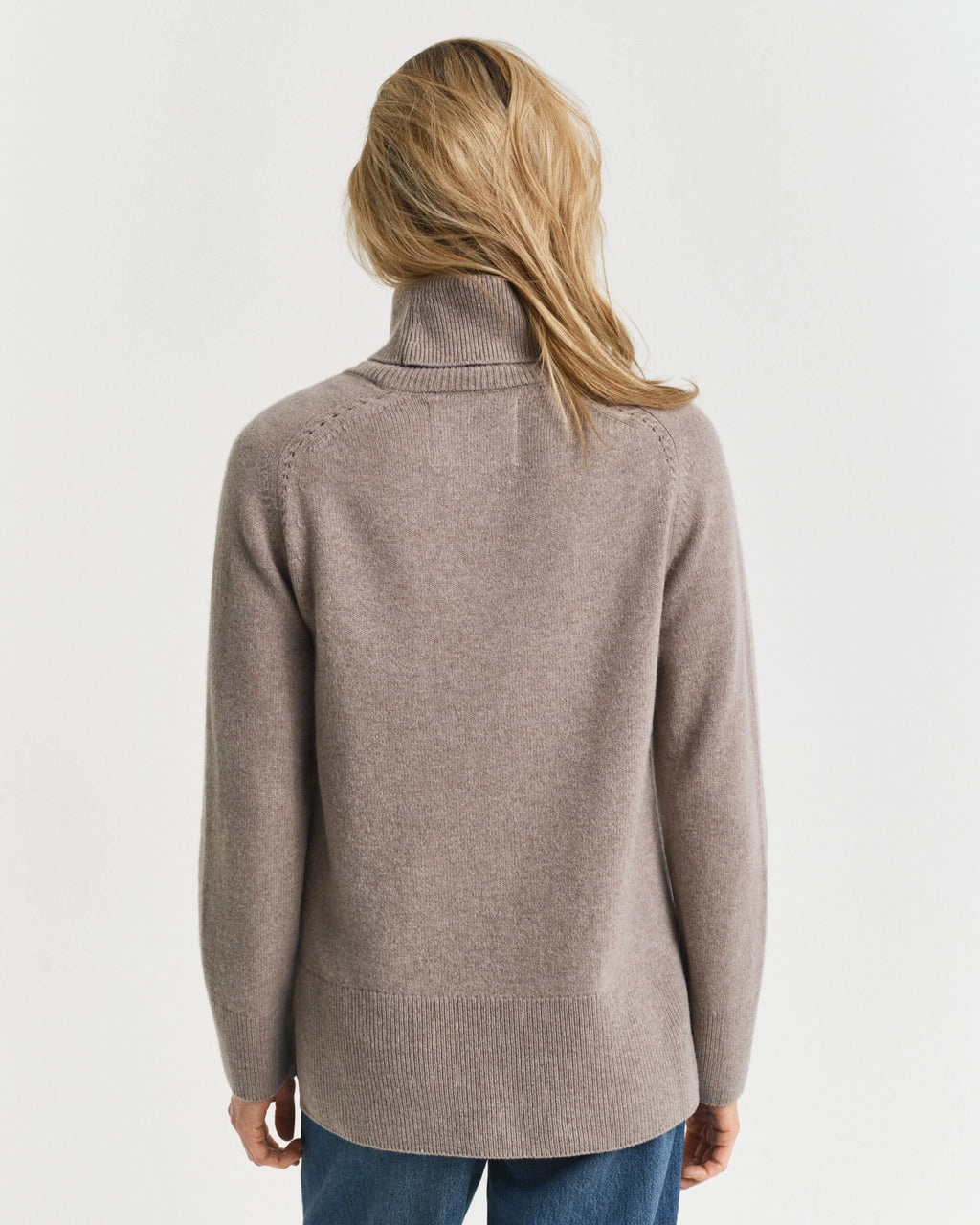 Person wearing a beige sweater on a plain background