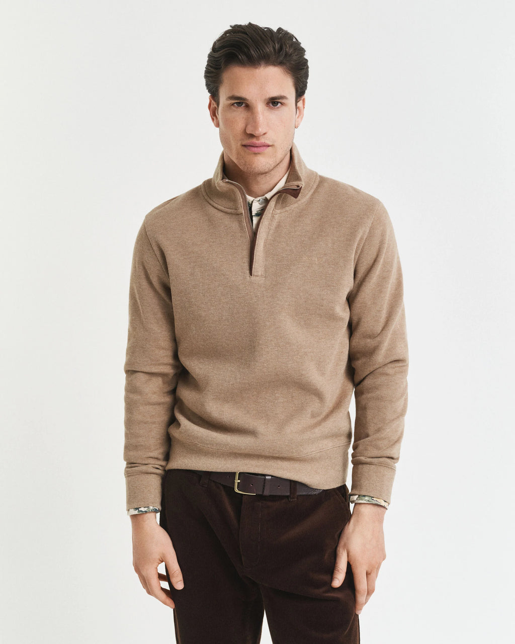 Man wearing a beige half-zip sweater on a white background