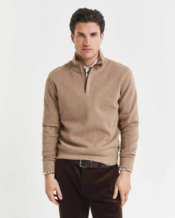 Man wearing a beige half-zip sweater on a white background