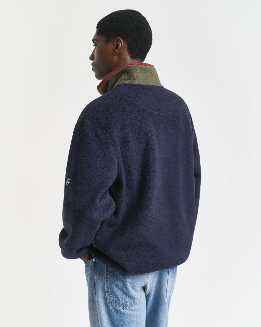 Person wearing a navy blue fleece jacket with a visible brand logo on a white background