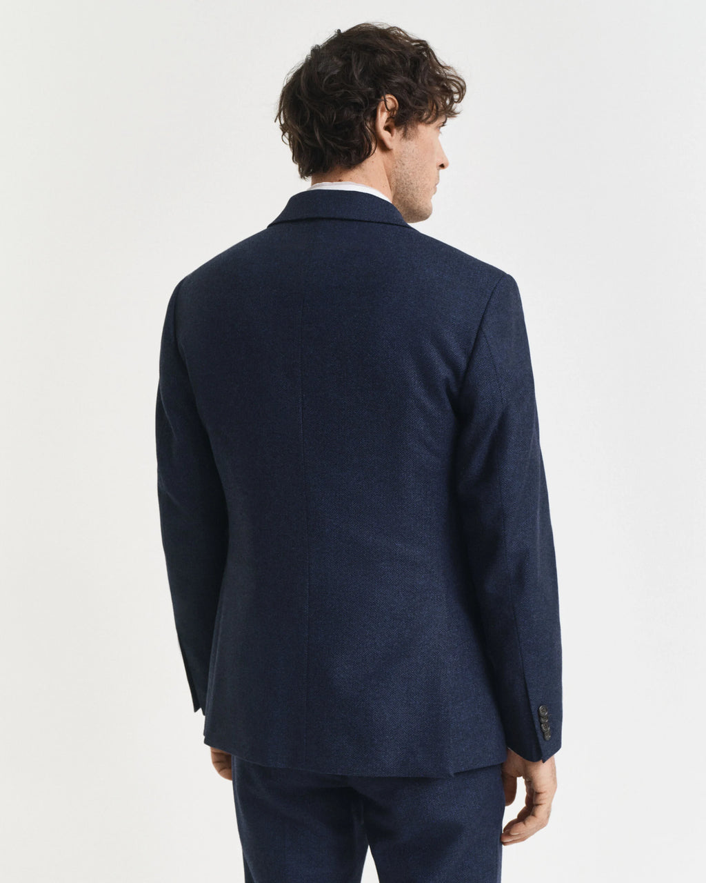 Man wearing a navy blue suit jacket on a light gray background