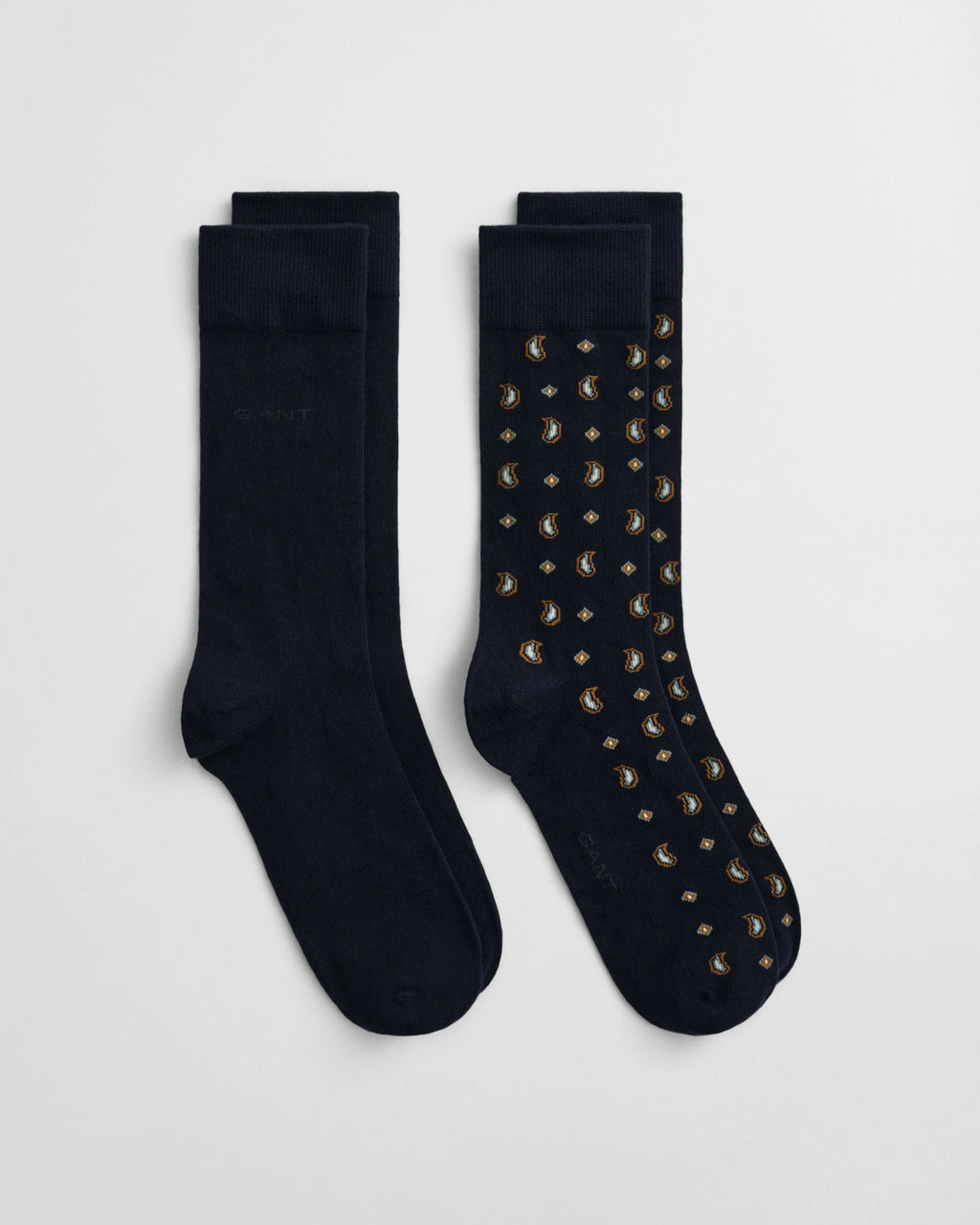 Two pairs of black socks with one having gold studs on a light gray background
